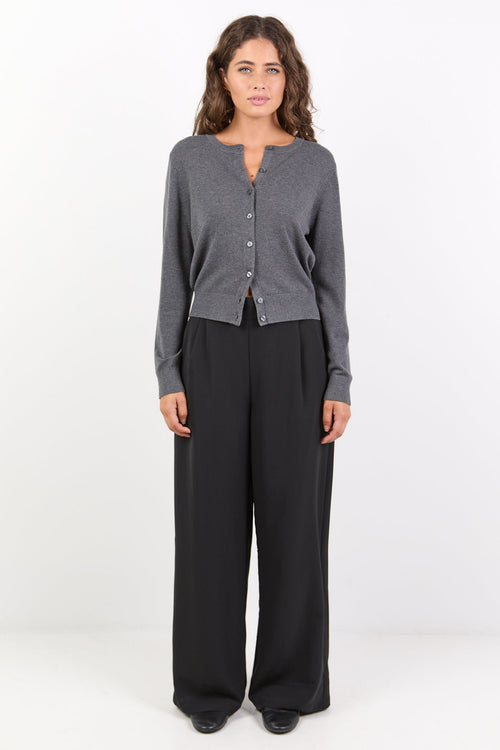 Woman wearing a gray cardigan and black pants on a white background