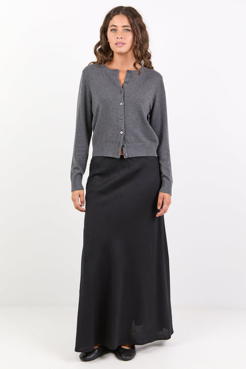 Woman wearing a gray cardigan and black skirt on a white background