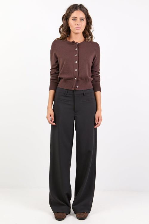 Woman wearing a brown cardigan and black pants on a white background