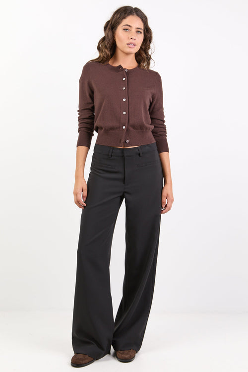 Woman wearing a brown cardigan and black pants on a white background