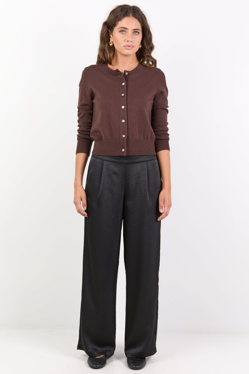 Woman wearing a brown cardigan and black pants on a white background