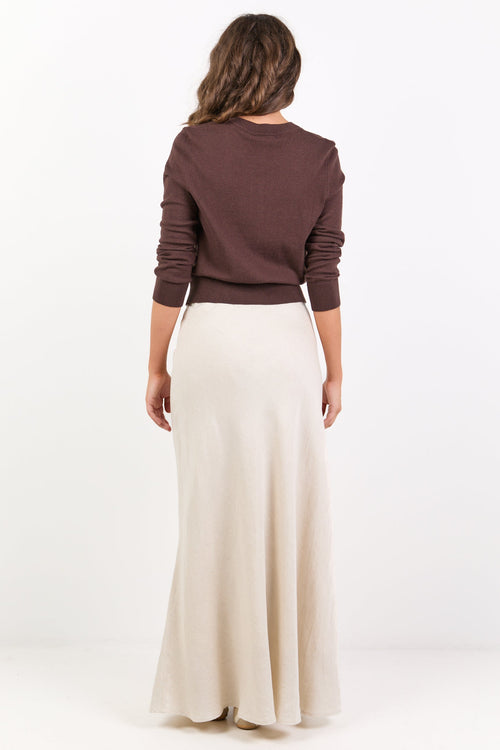 Woman wearing a brown sweater and white skirt on a white background