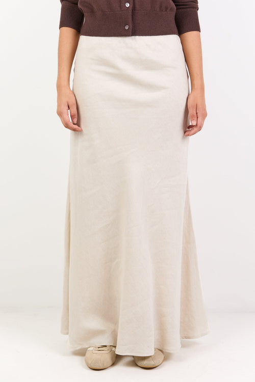 Person wearing a brown button-up shirt and white skirt on a white background