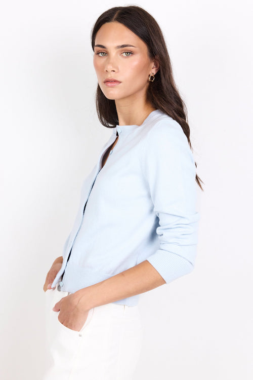 Woman wearing a light blue cardigan against a white background