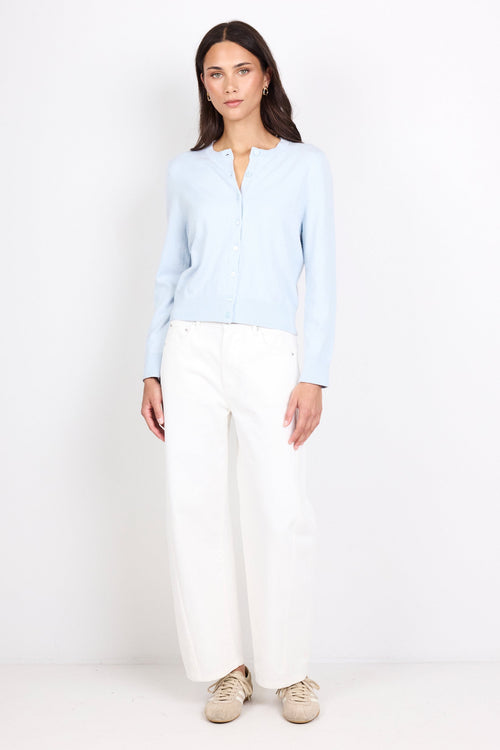 Woman wearing a light blue shirt and white pants on a white background