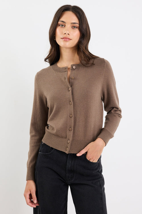 Woman wearing a brown cardigan and black pants against a white background