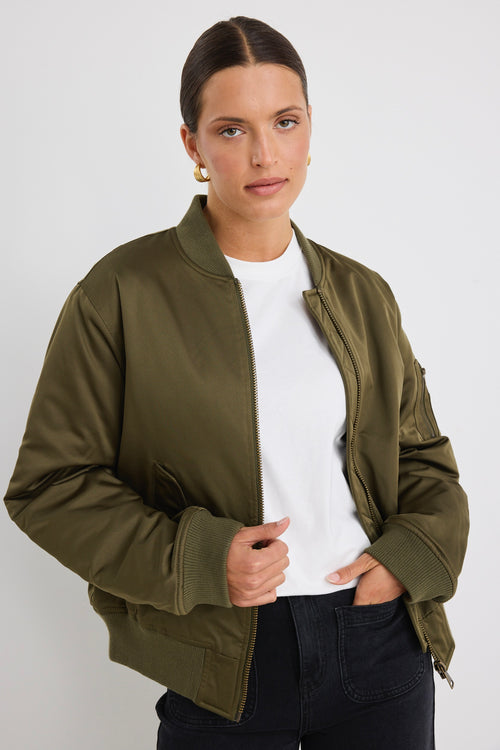 Model wears a khaki bomber jacket with black jeans and a white tee