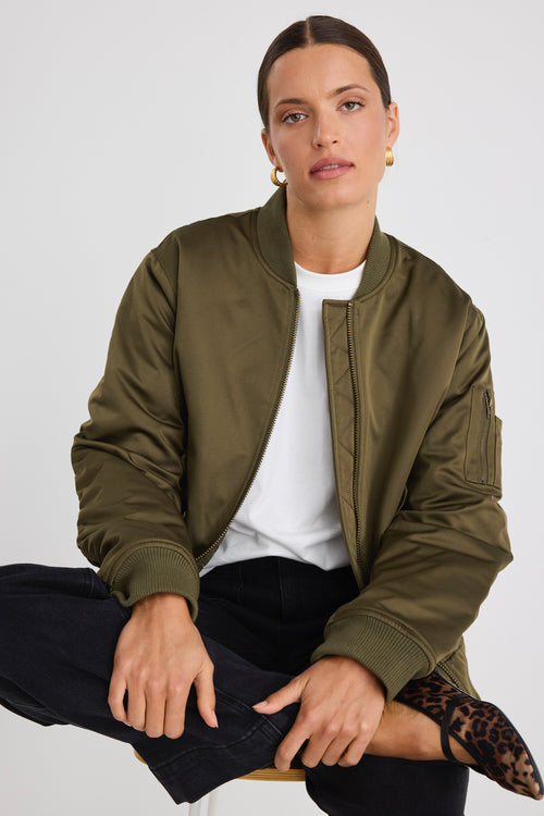 Model wears a khaki bomber jacket with black jeans and a white tee