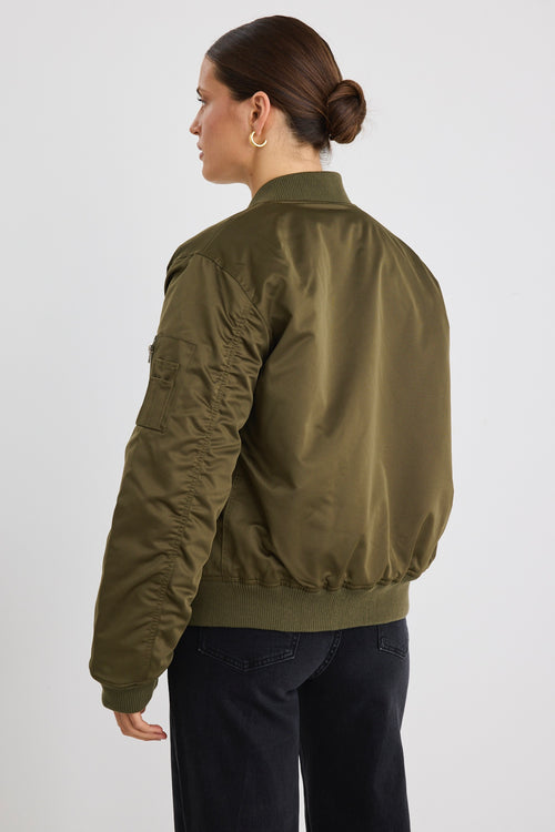 Model wears a khaki bomber jacket with black jeans and a white tee