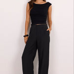 A woman modeling a black sleeveless top and matching black wide-leg pants against a plain white studio background.