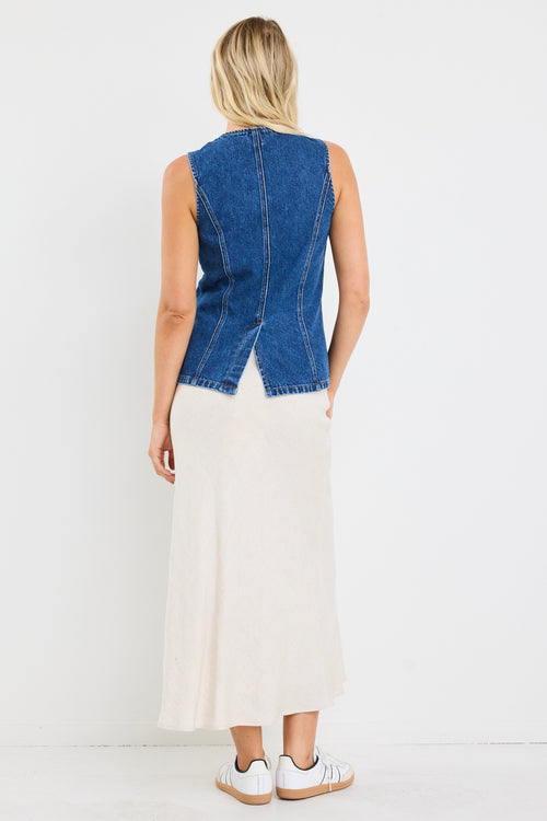 model wears a blue denim vest with a beige linen midi skirt