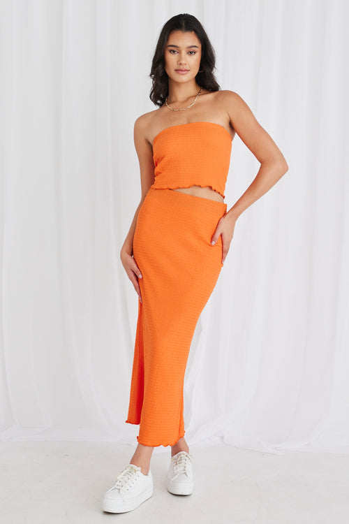 Model wearing orange bandeau top and maxi skirt set