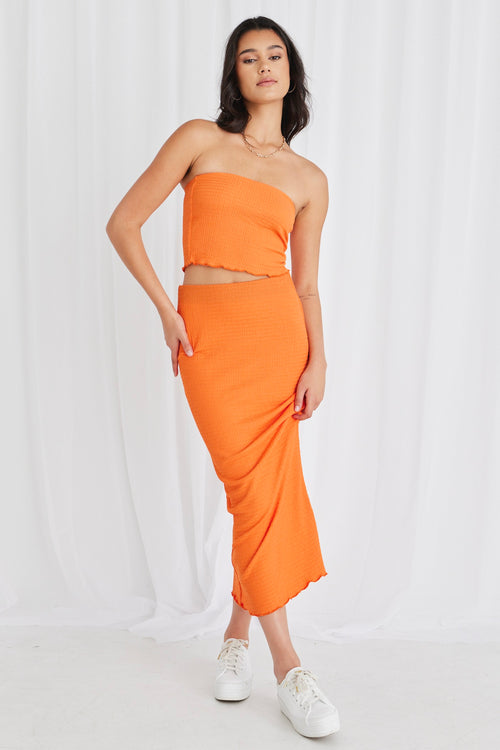 Model wearing orange bandeau top and maxi skirt set