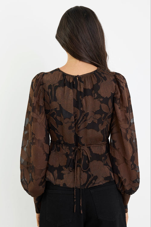 Woman wearing a brown floral blouse with puff sleeves on a white background