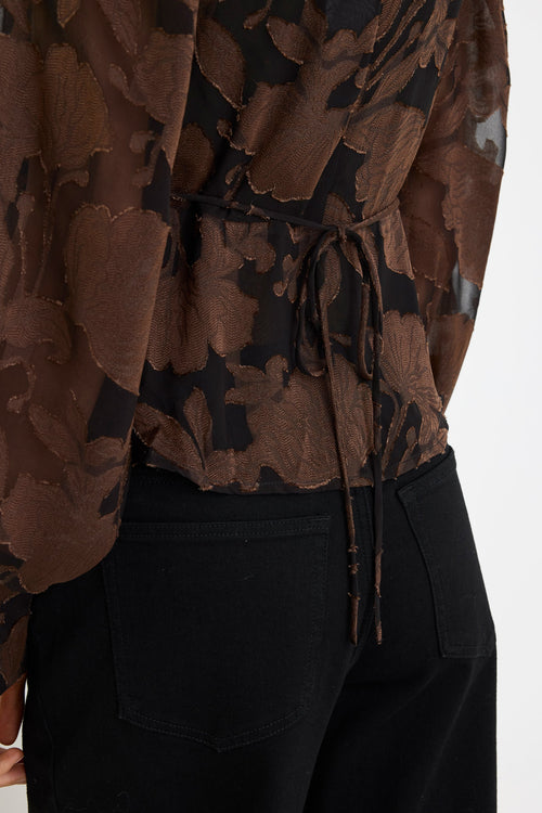 Brown floral-patterned top with a tie waist and black pants on a white background