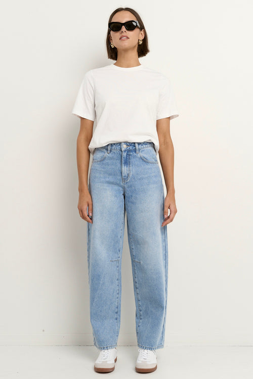 Woman wearing high-rise, light blue wide-leg jeans with a white tee and sneakers, styled in a relaxed, casual look.