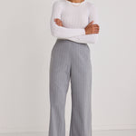 model wears white long sleeve top and grey pinstripe pants and white sneakers