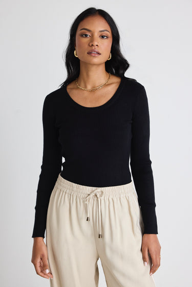 Model wears black long sleeve top with beige pants