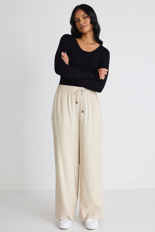 Model wears black long sleeve top with beige pants