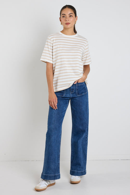 Model wears a white and ecru stripe shirt with blue jeans 