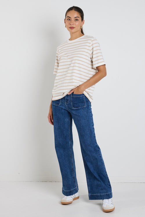 Model wears a white and ecru stripe shirt with blue jeans 