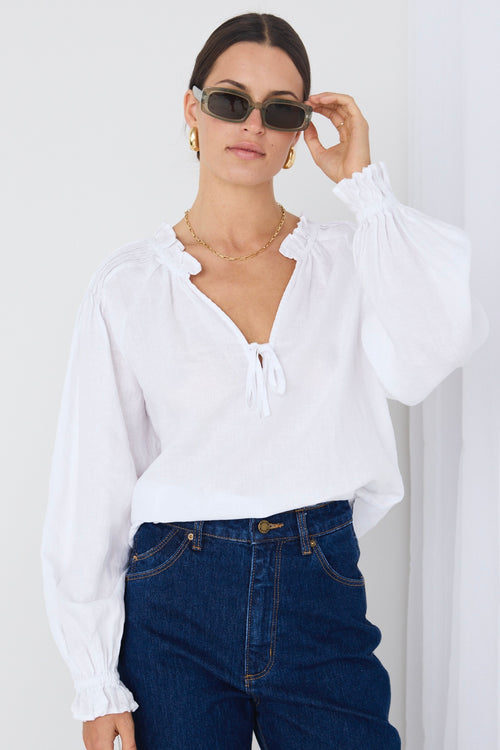 model wears white long sleeve top and blue denim jeans