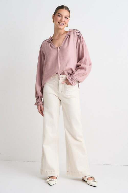 model wears pink long sleeve linen top and light beige denim jeans