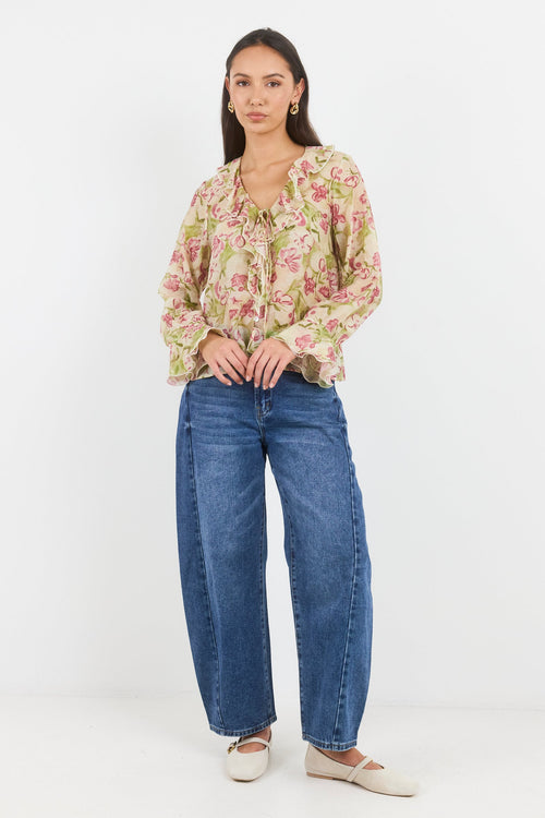 Woman wearing a floral blouse and blue jeans on a white background