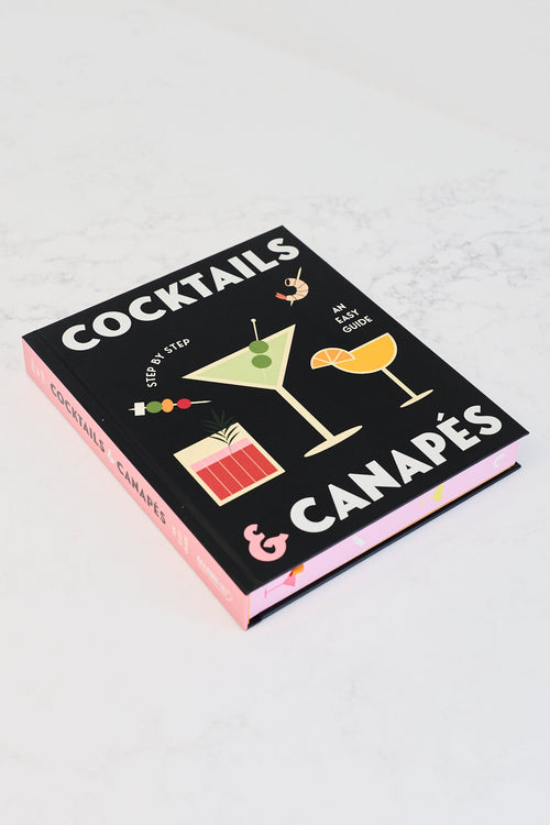 A book titled 'COCKTAILS & CANAPÉS' resting on a white marble countertop in a kitchen setting.