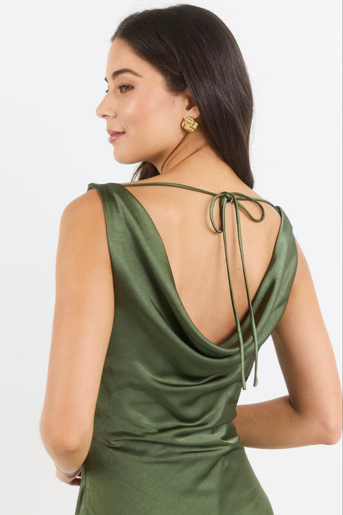 A woman shown from the back wearing an olive green satin slip dress with a tie-back neckline, photographed against a clean white studio background.