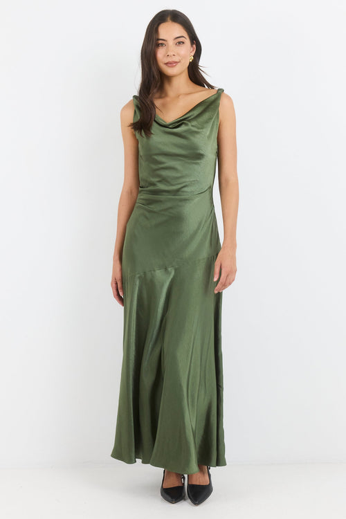 A woman modeling a sleeveless olive green satin maxi dress with a draped neckline, standing against a plain white studio background.