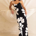 Woman wearing a black and white floral dress in front of a large shell sculpture.