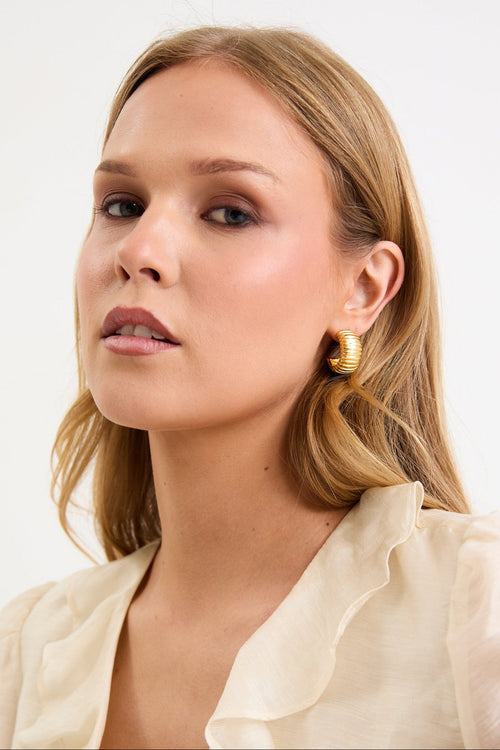 Woman wearing a beige blouse with ruffled details on a white background
