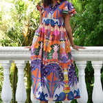 Woman wearing a colorful patterned dress standing on a stone path with greenery in the background
