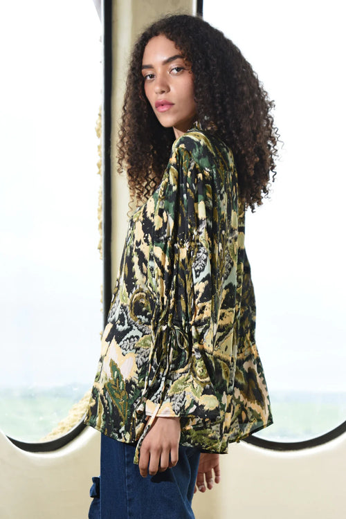 Woman wearing a patterned top with a scenic background