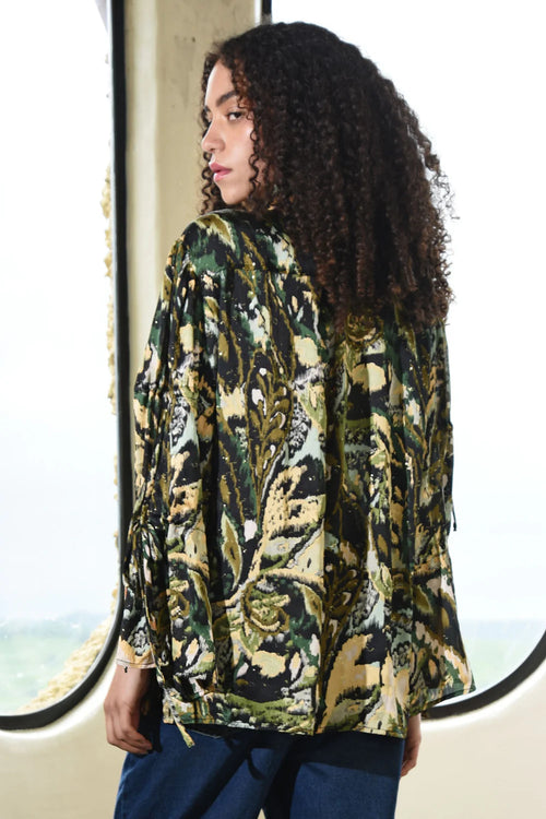 Woman wearing a patterned jacket standing in front of a window