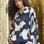 Woman wearing a floral patterned shirt with a blurred natural background