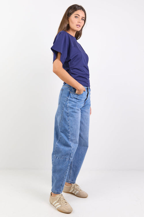 Woman wearing a navy tee and blue jeans on a white background