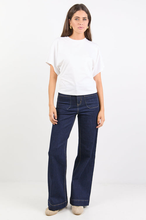 Woman wearing a white top and blue jeans on a white background