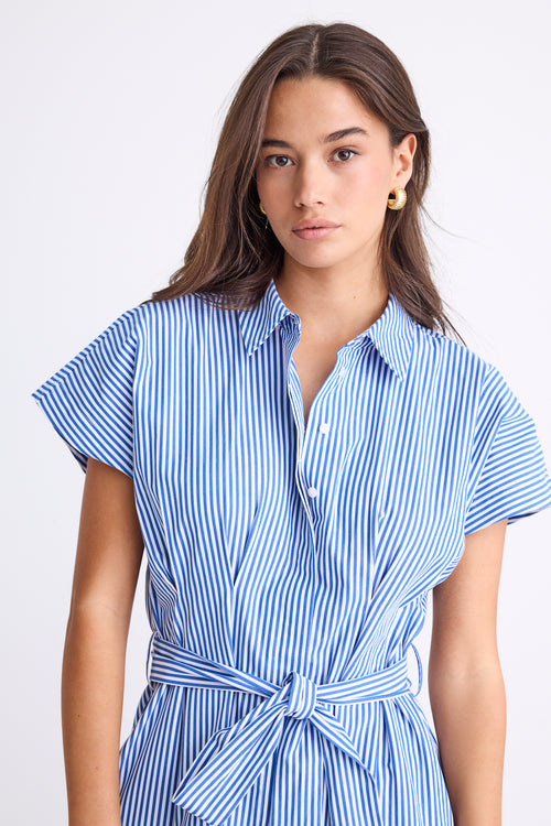 Woman wearing a bright blue striped midi shirt dress with short sleeves, button front, waist tie, and pleated skirt.