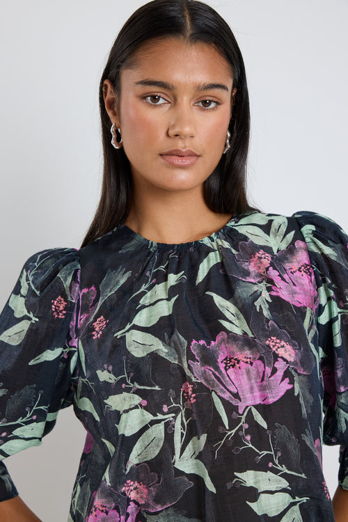 Model wears a black floral mid sleeve blouse top with blue jeans. 