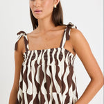 Woman wearing a brown and white geo print top and white jeans