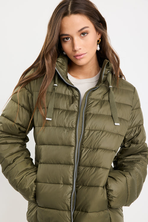 Woman wearing a green puffer jacket on a white background