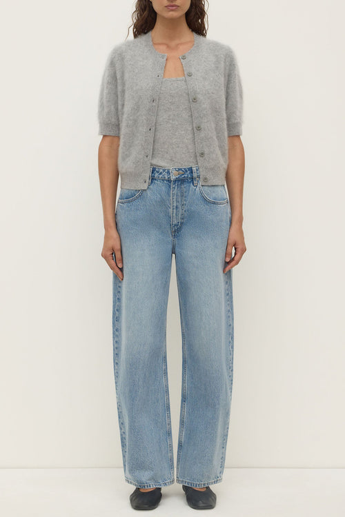 Person wearing a gray cardigan and blue jeans on a white background