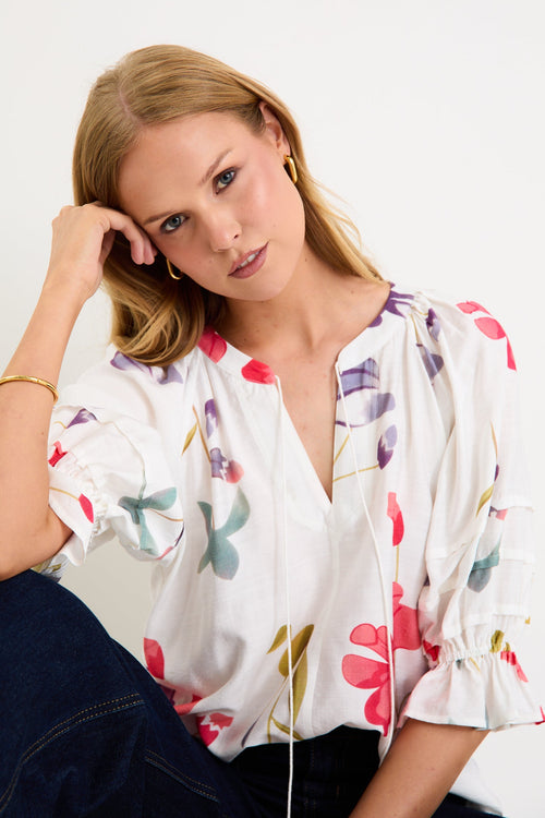 Woman wearing a cream floral poppy top and blue jeans