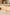 Two stemless wine glasses with an orange and white marbled pattern, set on a light marble kitchen counter next to a charcuterie board with cheese, grapes, and crackers.