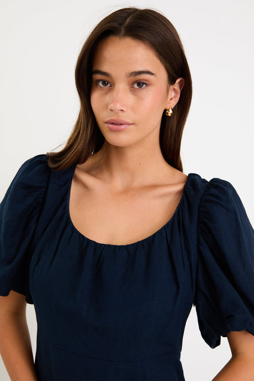 Woman wearing navy blue maxi dress with puff sleeves.