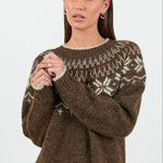 Woman wearing a brown knitted sweater with a pattern on a white background