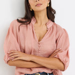 model wears a pink blouse with light blue jeans