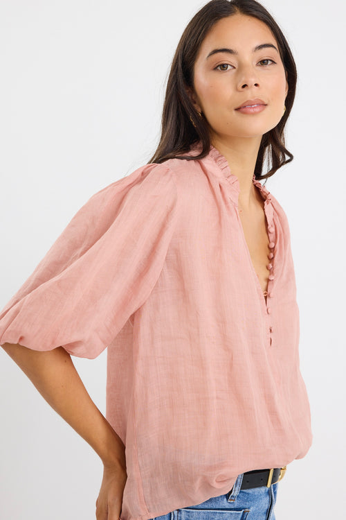 model wears a pink blouse with light blue jeans